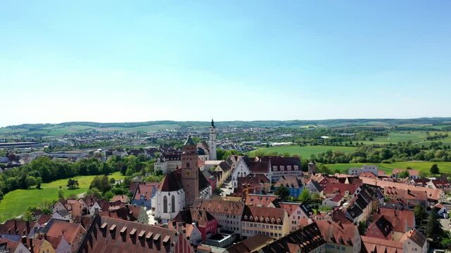 Luftaufnahme von Donauw&ouml;rth mit roten D&auml;chern, historischen Geb&auml;uden und einem markanten Turm, eingebettet in eine gr&uuml;ne Landschaft. Die Stadt bietet eine charmante Kulisse. 