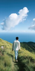 Fototapeta premium Young african male walking on grassy hill overlooking ocean under clear sky