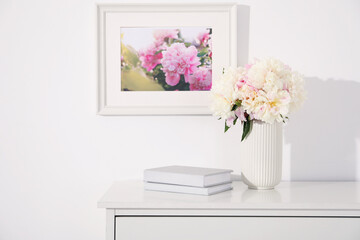 Bouquet of beautiful peonies and books on table indoors