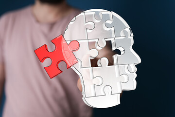 Conceptual image of a human head made of puzzle pieces, with one piece being added. Represents...