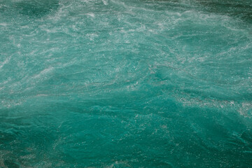 Vivid turquoise mountain river water with natural wave patterns, ripples and smooth movement....