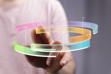 Person interacting with a colorful 3D circular chart.  Data analysis, technology concept.