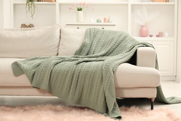 Green woolen blanket on sofa in room