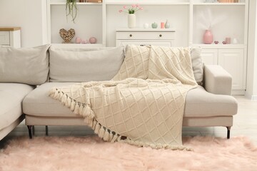 Beige woolen blanket on sofa in room