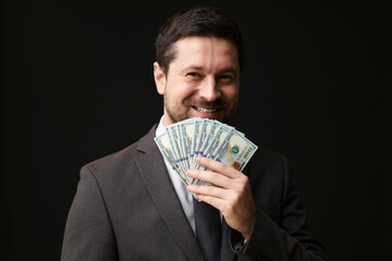 Happy greedy banker with dollar banknotes on black background