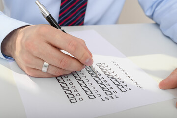 A man completes a test, marking answers a b c or d