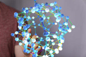 Person interacts with a 3D network, representing connection, data, or technology.