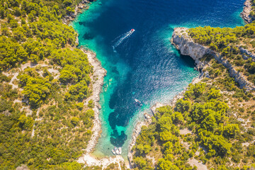 Top down aerial view of Tatinja Beach on the southern side of Solta Island, Croatia, revealing its unique curved shoreline, turquoise waters, rocky surroundings, and untouched landscape