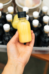 Immune boosting vitamin C health defending drink. Woman bottles with fresh turmeric, ginger and citrus juice shot in hand. Pure vegan Immunity system booster.