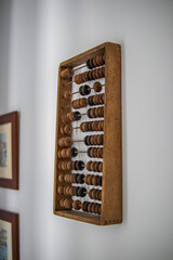 Vintage wooden abacus hanging on a white wall.