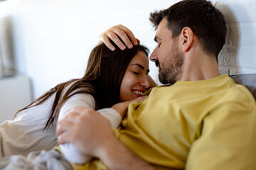 Happy couple cuddling in bed, sharing a tender moment filled with affection, warmth, and the joy of togetherness on a relaxing morning