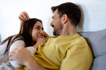 Young couple hugging and enjoying playful moments together on a cozy sofa at home, radiating love...