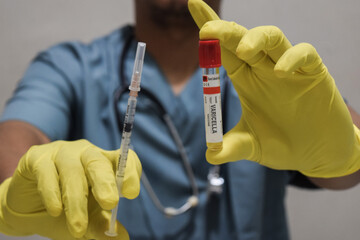 Text Varicella vaccine of is written on a bottle with background of a doctor with a syringe in a...