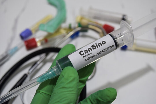 Cansino ad5-ncov covid-19 vaccination drug syringe in green gloved hands. Medical concept - Powered by Adobe
