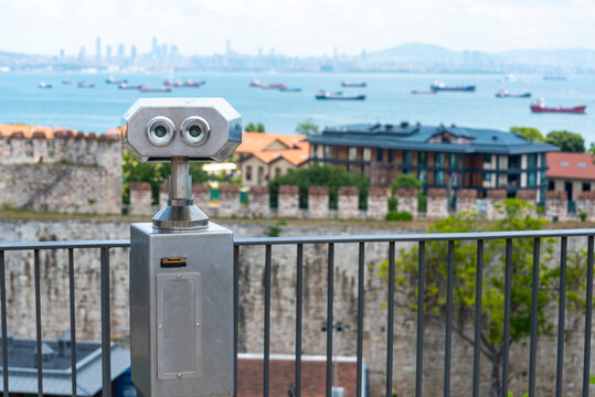 City skyline and ocean view captured from a lookout point featuring a telescope and historic fortifications in the background