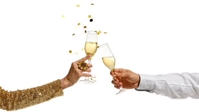 Male and female hands clinking champagne flutes with sparkling wine as golden confetti falls in air against white background. Concept of celebration, luxury, festive moment.