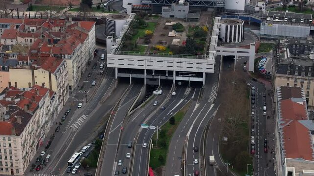 Aerial perspective capturing Lyon Perrache interchange and its hanging garden, showcasing intricate road network with vehicles navigating multi level highway infrastructure