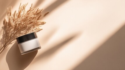 Minimalist beauty product display with soft shadows and dried grass on a beige background