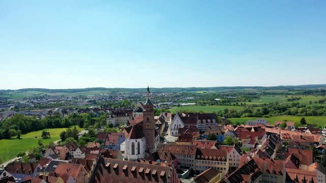 Luftaufnahme von Donauw&ouml;rth mit roten D&auml;chern, historischen Geb&auml;uden und einem markanten Turm, eingebettet in eine gr&uuml;ne Landschaft. Die Stadt bietet eine charmante Kulisse. 