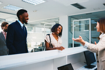 Business people arriving at office front desk talking with receptionist