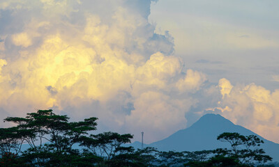 Golden-yellow clouds glow in the evening sky, illuminated by the warm rays of the setting sun,...