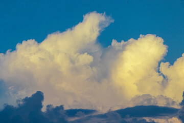 Golden-yellow clouds glow in the evening sky, illuminated by the warm rays of the setting sun,...