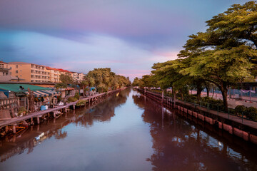 Obraz premium Urban Canal with Riverside Houses and Green Trees at Sunset