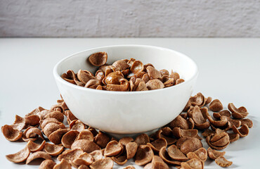 Chocolate corn flakes with milk in a bowl on white background