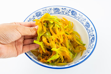 A bowl of blanched fresh daylily on a white background