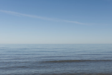 Blue sky with small string of clouds and the ocean.