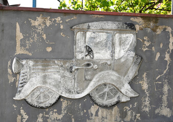 Concrete relief of a vintage car on a weathered wall in an urban environment