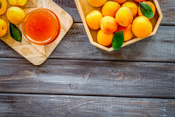 Healthy breakfast. Apricot jam in jar near fresh fruits on dark wooden background top view frame copy space