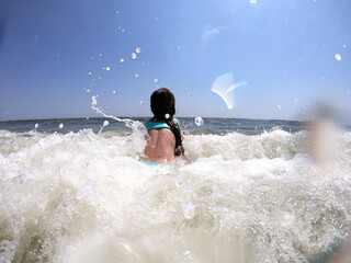Powerful ocean waves splashing on child girl in summer vacation