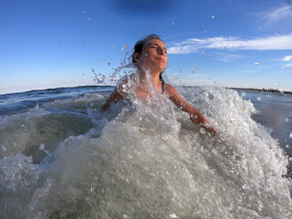 Powerful ocean waves splashing on child girl in summer vacation