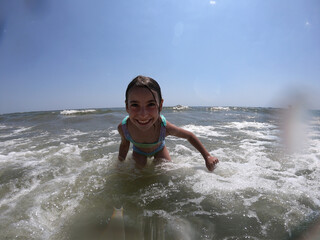 Powerful ocean waves splashing on child girl in summer vacation