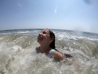 Powerful ocean waves splashing on child girl in summer vacation