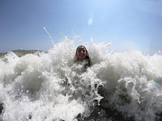Powerful ocean waves splashing on child girl in summer vacation