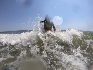 Powerful ocean waves splashing on child girl in summer vacation