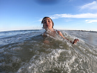 Powerful ocean waves splashing on child girl in summer vacation