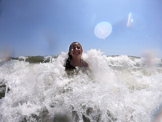 Powerful ocean waves splashing on child girl in summer vacation