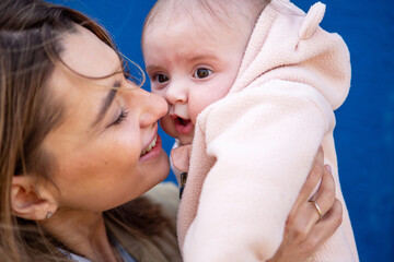 Close up of a loving mother nuzzling her baby in a soft pink outfit