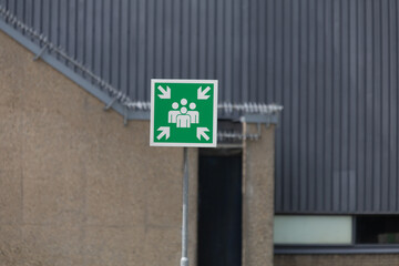 A clear green sign indicates an emergency assembly point, a crucial safety feature in public or institutional spaces.