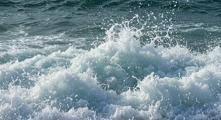 Dramatic close-up of ocean waves crashing with splashes and sea foam in sunlight