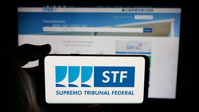Stuttgart, Germany - 06-09-2025: Person holding cellphone with logo of Brazil court Supremo Tribunal Federal (STF) on screen in front of webpage. Focus on phone display.