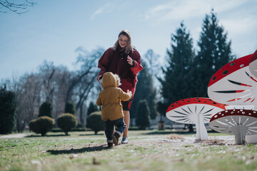 A cheerful interaction between mother and child unfolds in a park. Creative mushroom shaped...