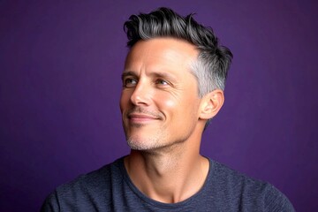 Fototapeta premium Purple solid background. Conceptual art of style for aging men. Fashionable men's mid fade haircut - midlife white man with black hair. A man with timeless elegance and a natural smile.