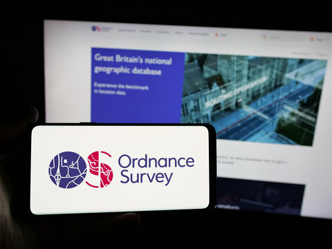 Stuttgart, Germany - 06-09-2025: Person holding smartphone with logo of British mapping agency Ordnance Survey (OS) on screen in front of website. Focus on phone display.