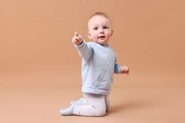 Cute little baby crawling on beige background