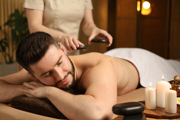 Obraz premium Man receiving relaxing massage with stones in spa salon