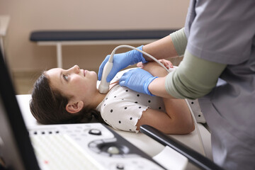 Sonographer conducting girl's thyroid gland ultrasound examination in clinic, closeup